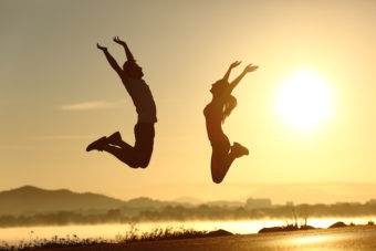 Happy couple jumping at the sunset